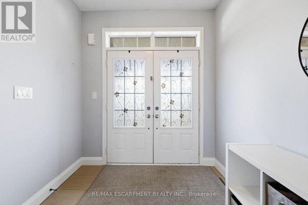 Interior view of the front entrance with double glass doors and a grey rug. - 47 Larry Crescent, Haldimand
