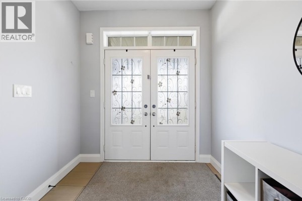 Interior view of a home entrance with double glass doors and a grey rug. - 47 Larry Crescent, Caledonia