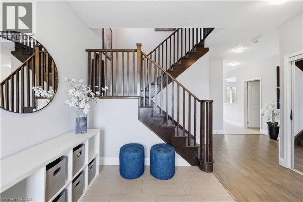 Interior view of a home entrance and staircase with wood railings and blue ottomans. - 47 Larry Crescent, Caledonia