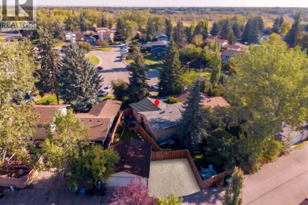 Aerial view of the duplex with surrounding trees and neighboring properties. - 47 Midvalley Rise Se, Calgary