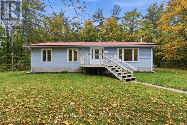 Front view of a light blue bungalow with a red roof, white railings, and a pathway leading to the door. - 47 Reynolds Road, Madoc