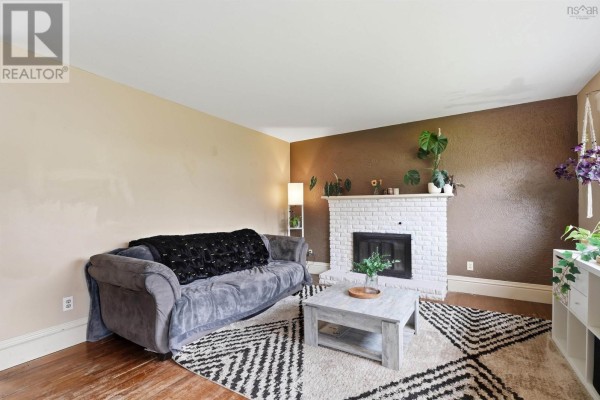 Living room with a gray sofa, white brick fireplace, and a patterned rug. - 47 Weyburn Road, Woodlawn