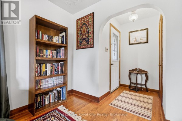 Foyer with a wooden bookshelf, arched doorway, and oriental rug on hardwood floor. - 470 Dublin Street, Wellington North