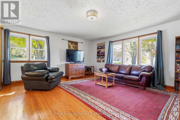 Living room with two large windows overlooking trees and a red oriental rug. - 470 Dublin Street, Wellington North