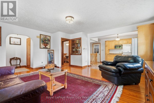View of the living room, foyer, and kitchen, featuring hardwood floors and arched doorways. - 470 Dublin Street, Wellington North