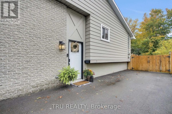 Front entrance with a white door, lantern light, and a wooden fence to the right. - 470 Joseph Street, Carleton Place