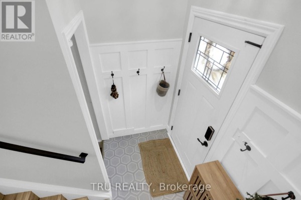 Foyer with white wainscoting, hexagonal floor tiles, a white door, and coat hooks. - 470 Joseph Street, Carleton Place