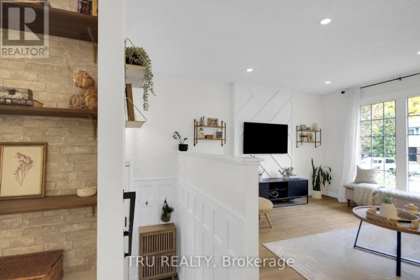 Living room with white walls, a television, coffee table, window seat, and wooden floor. - 470 Joseph Street, Carleton Place