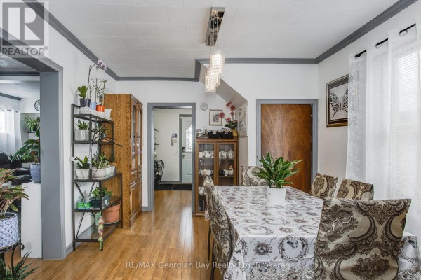 Dining room with a table set for eight, wood floors, doorway to kitchen, and a wooden display cabinet. - 470 Manly Street, Midland