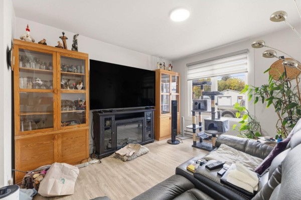 Living room with a large TV, electric fireplace, and wooden display cabinets. - 470 Rue Des Pins, Gatineau