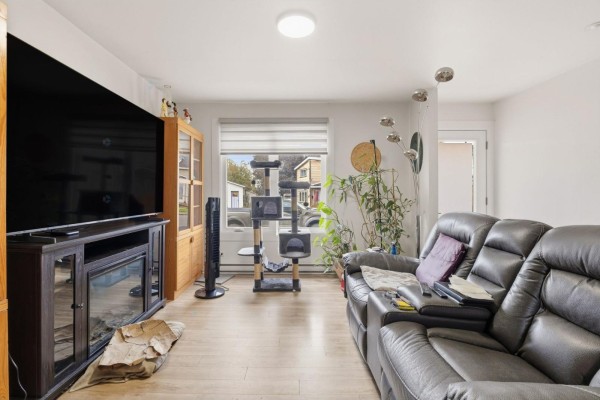 Living room with a large TV, electric fireplace, and leather couches. - 470 Rue Des Pins, Gatineau