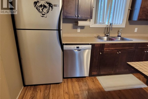 Close-up of kitchen area with dishwasher, sink, and stainless steel refrigerator. - 4705 Tribune Street, Macklin