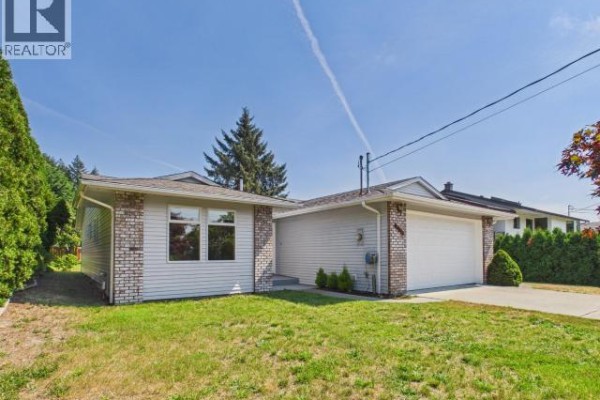 Side view of the light blue house, showing siding, windows, and a concrete path. - 4706 Ontario Ave, Powell River