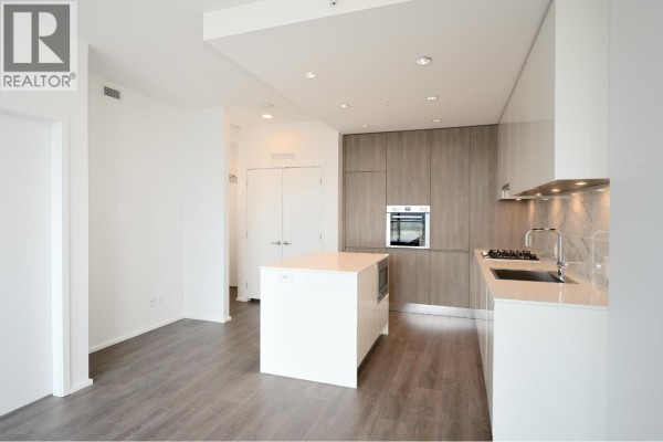 View of the modern kitchen from the living room, featuring an island and counter. - 4708 4650 Brentwood Drive, Burnaby