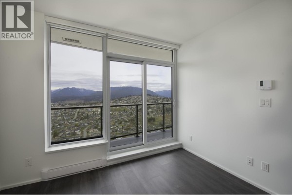 Living area with large windows overlooking a city and mountain view. - 4708 4650 Brentwood Drive, Burnaby