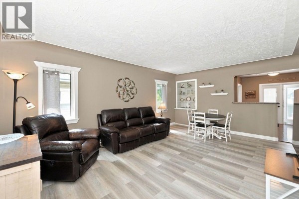 Living room with brown leather recliners, a sofa, and a round dining table with chairs. - 4708 47 Street, Camrose