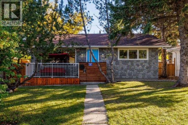 A concrete pathway leads to the front entrance of a bungalow with a stone facade. - 4711 26 Avenue Sw, Calgary