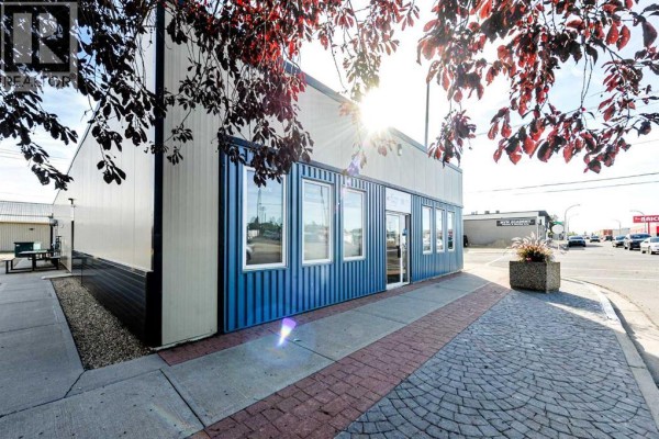 Side view of the commercial building with blue corrugated metal siding and windows. - 4711 51 Avenue, Camrose
