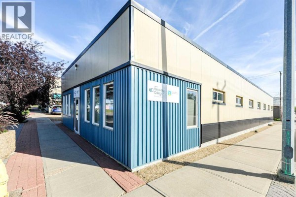 Corner view of the commercial building showing blue siding and beige panels. - 4711 51 Avenue, Camrose