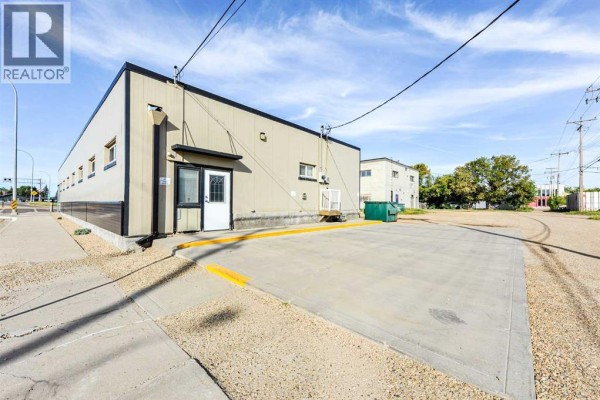 Rear exterior of the commercial building with a loading dock and parking area. - 4711 51 Avenue, Camrose