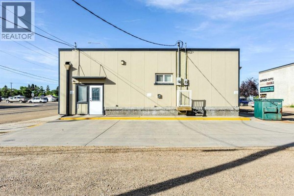 Back of the commercial building with a small platform and exterior utilities. - 4711 51 Avenue, Camrose