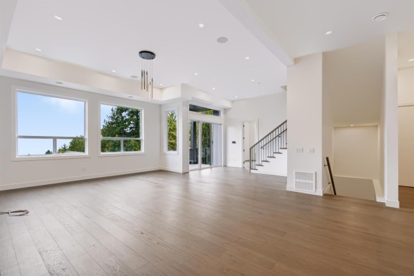Spacious open-concept living room with hardwood floors, large windows, and a modern chandelier. - 47136 Sylvan Drive, Promontory, Chilliwack