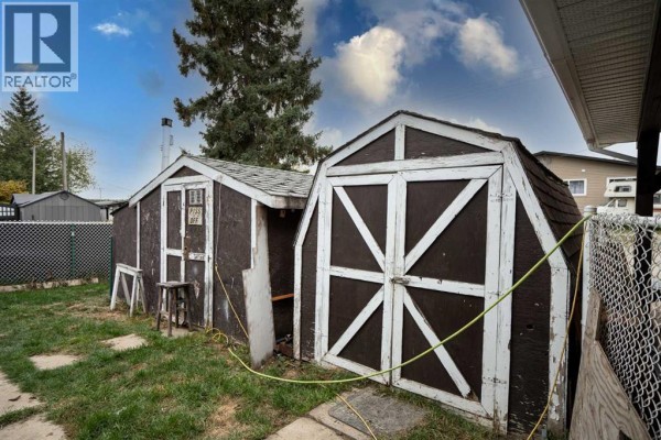 Two brown wooden sheds with white trim in a grassy yard. - 4716 49 Street, Caroline