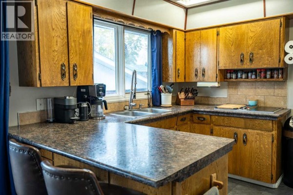 U-shaped kitchen with oak cabinets, laminate countertops, and stainless steel sink. - 4716 49 Street, Caroline