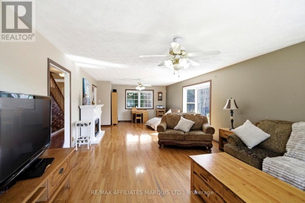 Living room with fireplace, hardwood floors, ceiling fans, sofas, and a desk - 4720 O'keefe Road South Stormont