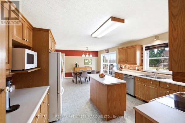 Kitchen with island, wood cabinets, and dining area - 4720 O'keefe Road South Stormont