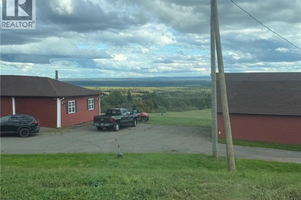 Red residential building and barn with vehicles parked outside, overlooking a vast landscape. - 47210 Homestead Road, Steeves Mountain