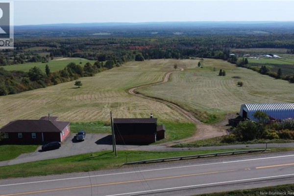 Aerial view of red residential building, barn, and large field with winding dirt road. - 47210 Homestead Road, Steeves Mountain