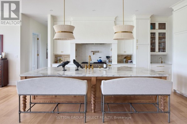 Kitchen island with marble countertop, seating, and modern pendant lights above. - 472715 Southgate 47 Side Road, Southgate
