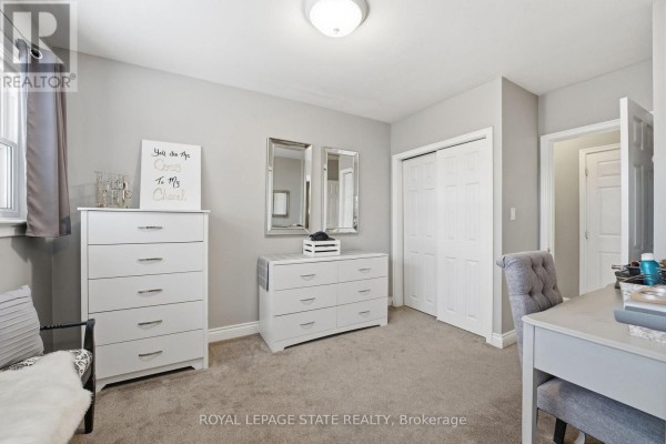 Living room with sectional sofa, ottoman, and large windows with plantation shutters - 473 Mohawk Road W Hamilton