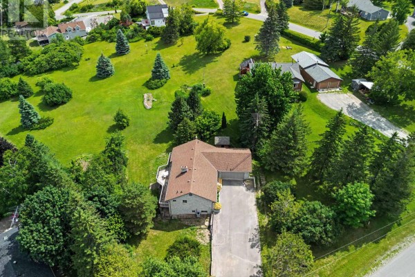 Aerial view of a large grey brick house with a long paved driveway and surrounding green landscape and trees. - 473 Sunset Crescent, Alnwick/haldimand