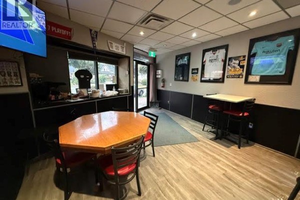 View of the dining area with a hexagonal table, chairs, and framed sports jerseys on the wall. - 4736 Valley Way, Niagara Falls