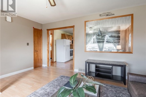 Living room with view into kitchen featuring white refrigerator and stainless steel appliances. - 4738 Fergus Avenue, Greater Sudbury