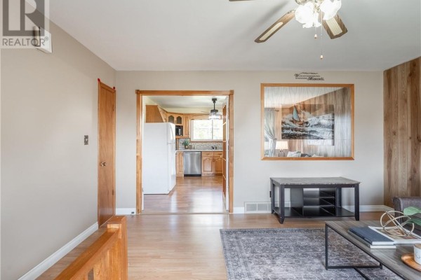 Living room looking towards kitchen with wooden cabinets, white appliances, and tiled backsplash. - 4738 Fergus Avenue, Greater Sudbury