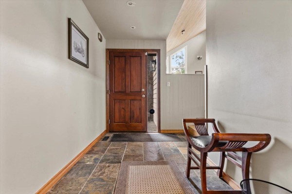 Interior entryway with slate tile floor, double wood doors, and two wooden bench seats. - 47390 Swallow Crescent, Little Mountain, Chilliwack