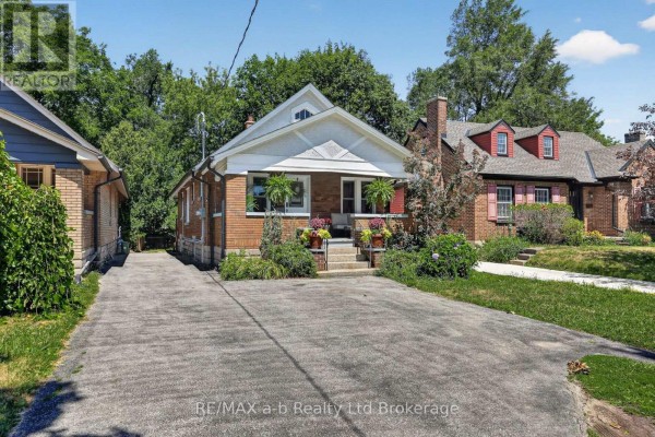 Street view of a brick house with a detached garage and landscaped yard. - 474 Cheapside Street, London East