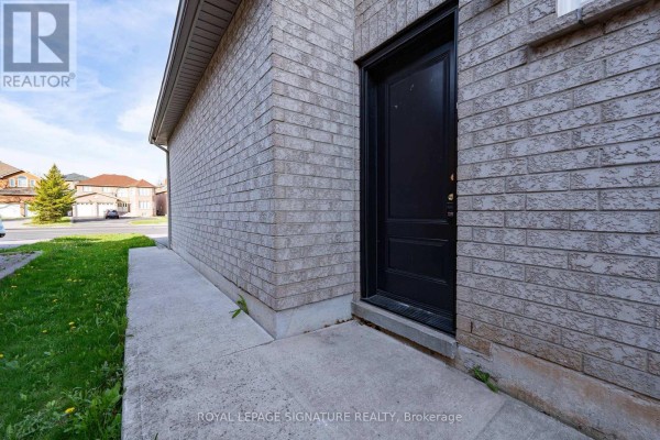 Side exterior view of a brick house showing a dark front door and concrete walkway. - 4742 Creditview Road, Mississauga