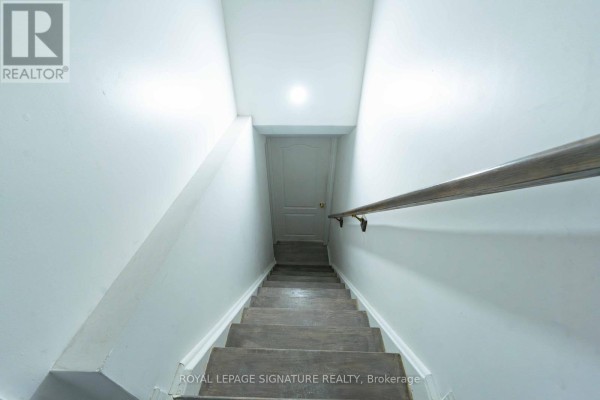 Interior view looking down a narrow, carpeted staircase with white walls and a wooden handrail. - 4742 Creditview Road, Mississauga