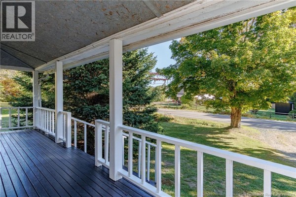 View from a covered porch with white railings, white columns, and trees visible in the background. - 4746 Route 102, Queenstown