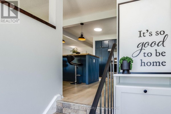 View from entryway towards open concept living space with blue kitchen island. - 475 Athabaska Street, Tay