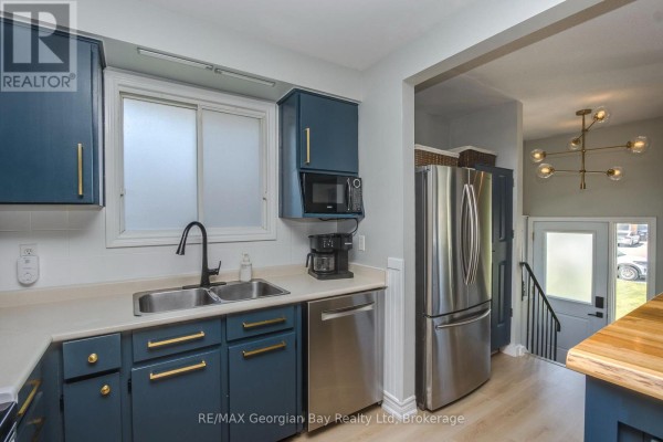 Kitchen with blue cabinetry, stainless steel appliances, and white countertops. - 475 Athabaska Street, Tay
