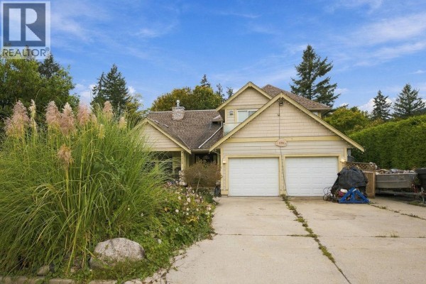 Front view of a light yellow house with two garage doors and landscaping. - 475 Harry Road, Gibsons