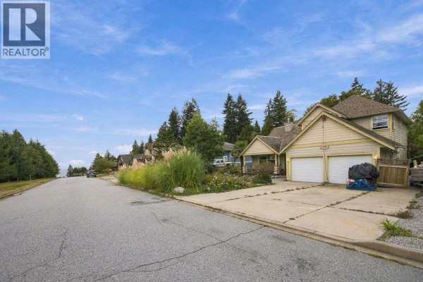 View of a street with houses on a gentle slope under a blue sky. - 475 Harry Road, Gibsons