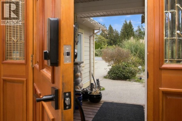 View from inside the open front door looking out to the driveway and landscaping. - 475 Harry Road, Gibsons