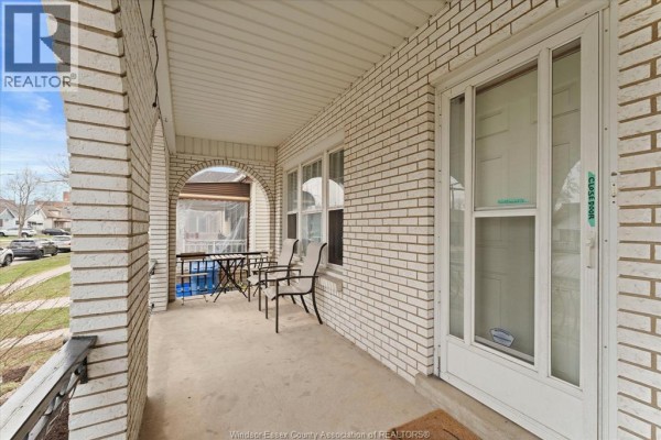 Dining area with wooden table and chairs next to a kitchen with white cabinets. - 475 Mckay Avenue, Windsor