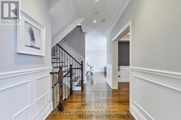 Interior hallway with a dark wood staircase, white wainscoting, and hardwood floors. - 475 Poplar Avenue, Ajax